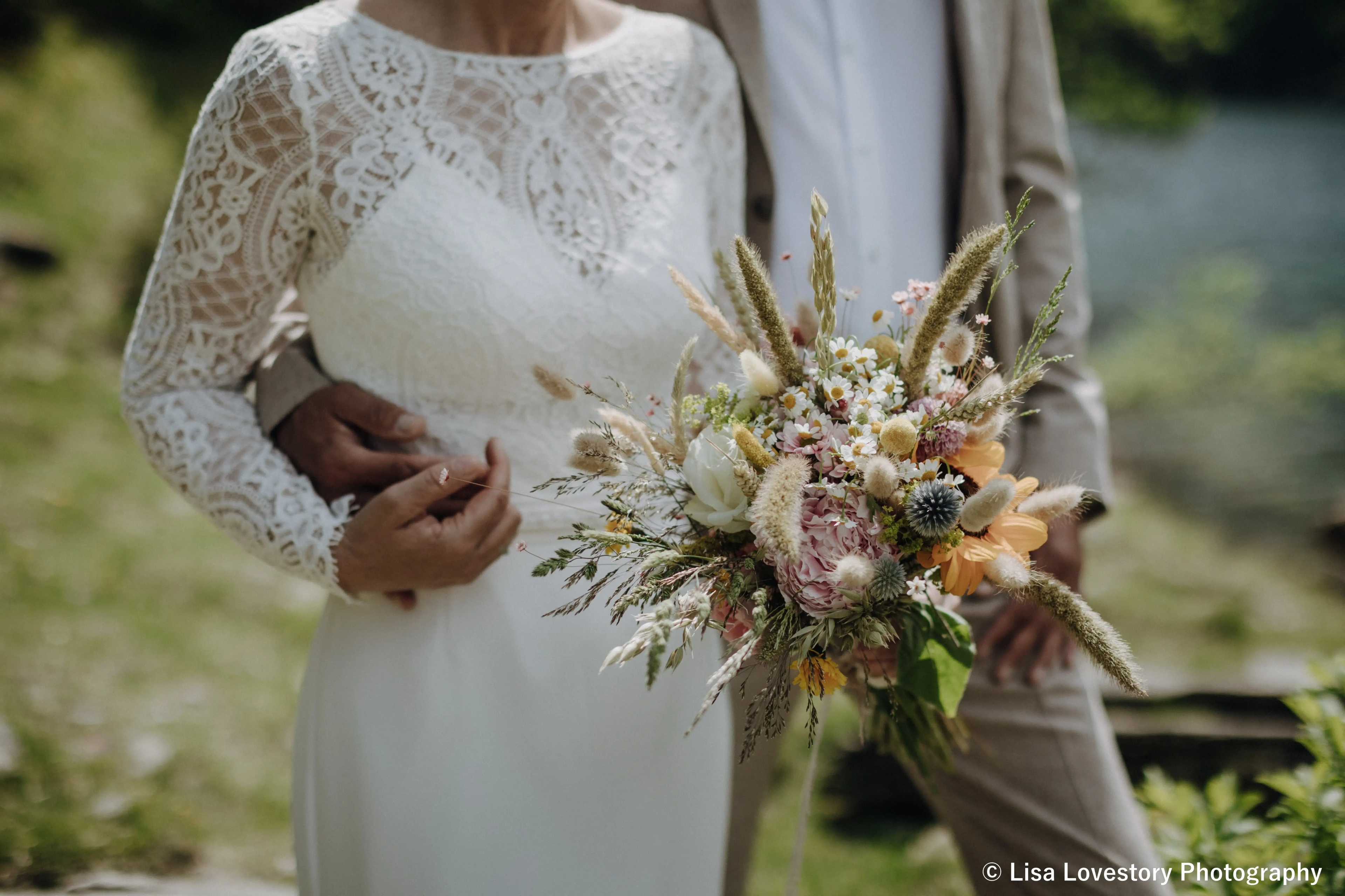 Brautpaar mit Blumenstrauß bei Hochzeit in Tirol